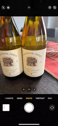 User scanning a QR code sticker on a bottle of wine. The QR code links the user to the wine.com app.