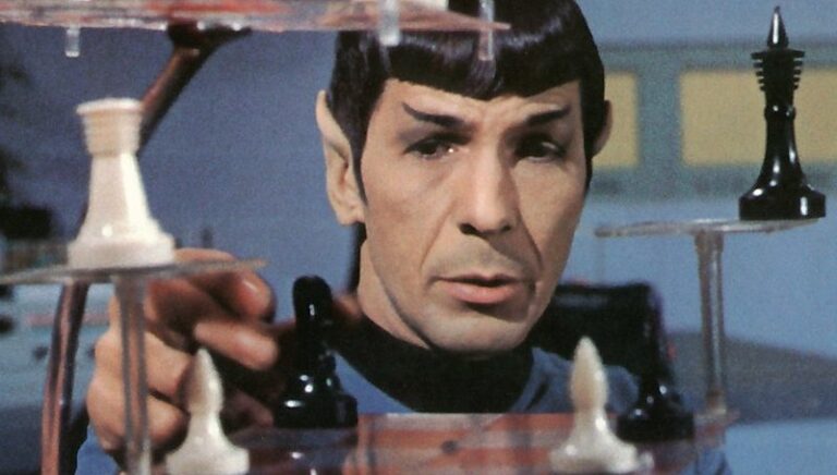 A person reaches out to a futuristic chess set with transparent layers, featuring black and white chess pieces in a sci-fi setting.