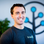 Branch CEO Alex Austin smiling at camera in a Branch t-shirt in front of the Branch logo glyph