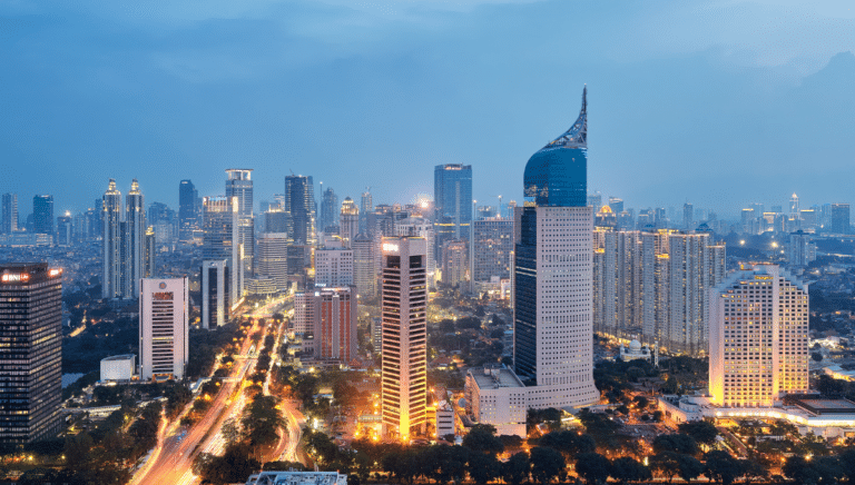 Twilight cityscape with illuminated skyscrapers and bustling traffic.